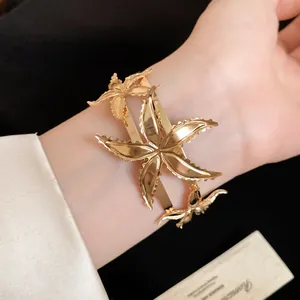 Primer plano de un brazalete de estrella de mar dorado en la muñeca, estilo retro.