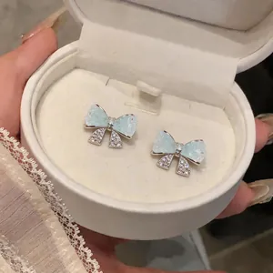 Detailansicht eleganter Schleifenohrringe mit minzgrünem Harz und glitzernden Steinen.