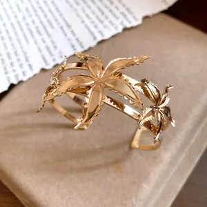 Primer plano de un brazalete abierto de metal dorado con diseño de estrella de mar.