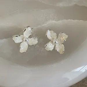 Close-up of elegant French style white enamel flower stud earrings with pearl centers