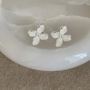 Detailed close-up of elegant floral earrings with white enamel petals and pearl center