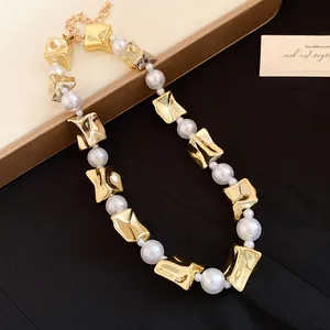 Close-up of vintage pearl necklace with irregular gold geometric beads on black fabric.