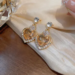Macro view of champagne heart-shaped earrings with diamond-encrusted silver needle