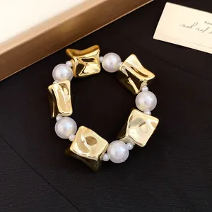 Close-up of retro style bracelet with alternating pearls and gold metallic blocks