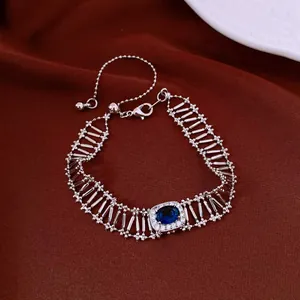 Vista dettagliata di un bracciale vintage in argento con zircone blu su tessuto rosso