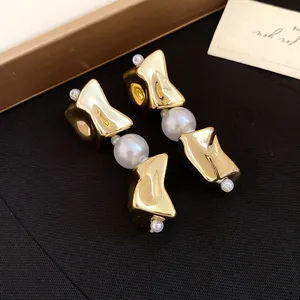 Close-up of vintage gold geometric earrings with pearl accents on black background