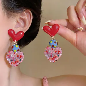 Detail view of colorful heart earrings with polka dot bead and crushed stone texture
