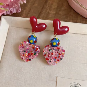 Close-up detail of colorful heart-shaped dangle earrings with sparkling crystal texture