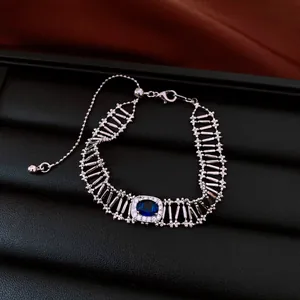 Dettaglio del bracciale vintage traforato con zircone blu ovale e catena argentata.