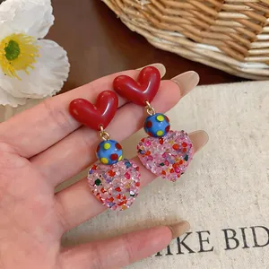 Detailed close-up of sweet heart-shaped drop earrings with colorful polka dot bead accents
