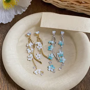 Close-up of elegant resin flower tassel earrings with zirconia studs in gold and silver