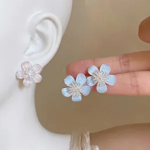 Sweet Korean style resin flower stud earrings with zircon center shown on ear of a model