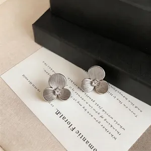 Elegant silver-toned camellia flower stud earrings with matte finish and center stone