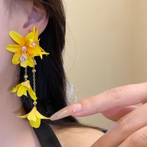 Detailed view of vibrant yellow fabric flower earrings with elegant pearl tassels
