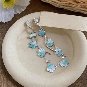 Close-up of light blue resin flower earrings with shimmering zircon and silver chains