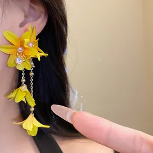 Close-up of yellow fabric flower earrings with pearl tassels and silver needles