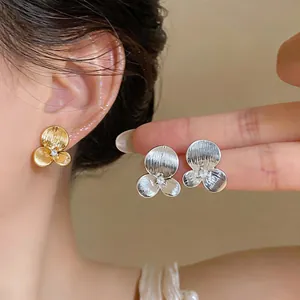 Detailed macro view of textured floral stud earrings in elegant gold and silver finishes