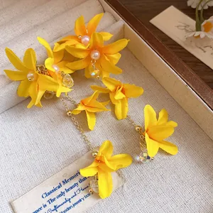 Close-up of sweet yellow fabric flower earrings with pearl and crystal tassels