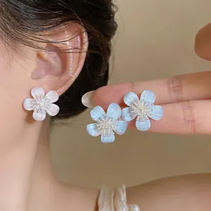 Close-up view of elegant resin flower stud earrings with shimmering zircon centers