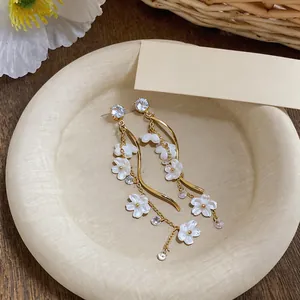 Detailed view of elegant resin flower and zirconia tassel earrings on a ceramic dish