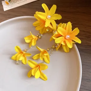 Detail view of handmade yellow fabric flower dangle earrings with pearls and crystals
