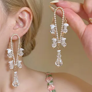 Elegantes pendientes de borla dorados estilo francés con brillantes y detalles de pétalos blancos
