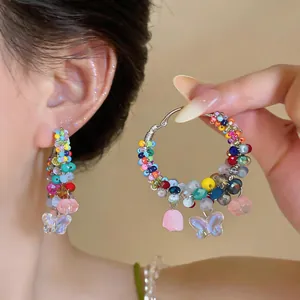 Close-up detail of colorful summer beaded hoop earrings featuring delicate butterfly charms