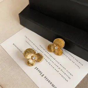 Macro detail of vintage gold camellia earrings with a central sparkling crystal.
