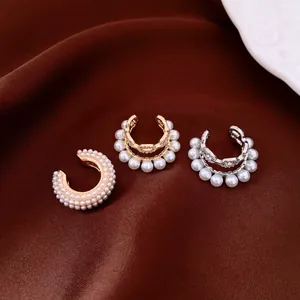 Close-up detail of French style pearl and zircon non-piercing ear cuffs on brown fabric