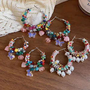 Detailed shot of vibrant dopamine beaded hoop earrings with pearl and butterfly charms.