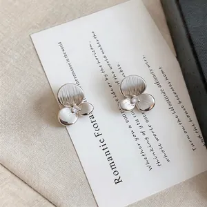 Close-up of camellia flower stud earrings with textured silver petals and central crystal