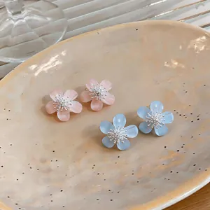 Close-up detail of sweet resin flower earrings with zircon centers in pink and blue colors