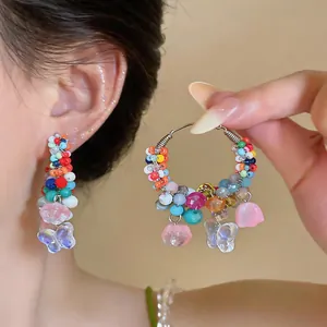 Detail view of vibrant colorful beaded hoop earrings with butterfly charms for summer vibe.