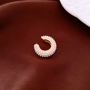 Detailed macro view of an elegant gold-plated ear cuff encrusted with small white pearls.