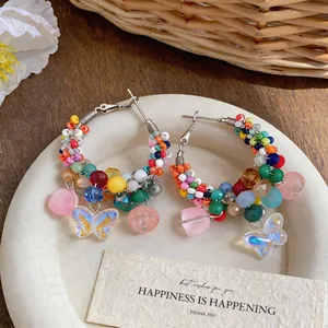 Detailed view of colorful beaded hoop earrings with butterfly charms in summer style