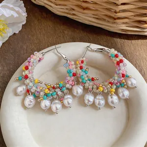 Close-up of colorful dopamine beaded hoop earrings with pearl charms.