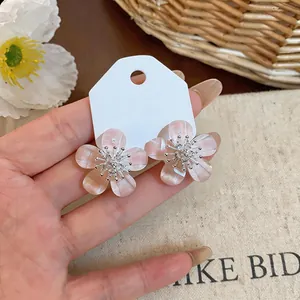 Detailed macro view of pink resin flower stud earrings with shimmering zircon centers