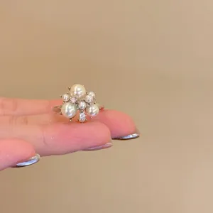Close-up of a vintage pearl cluster ring with elegant crystal accents worn on a finger