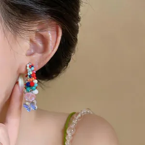 Close-up of vibrant colorful beaded earring with cute flower and butterfly charms