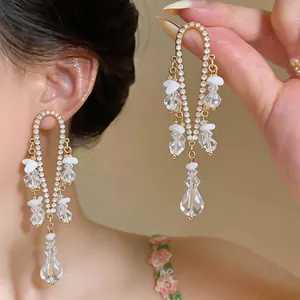 Detalle de pendientes largos dorados de estilo francés con cristales claros