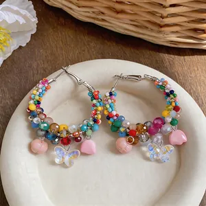 Macro view of colorful beaded hoop earrings featuring delicate butterfly and flower charms