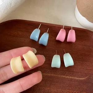 Gros plan de boucles d'oreilles en émail en forme de U bleu pastel, rose et vert.