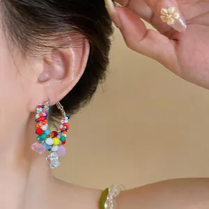 Macro close-up of a model wearing vibrant and colorful handmade beaded hoop earrings.