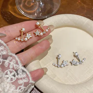 Dettaglio di eleganti orecchini a stella con perle e zirconi splendenti