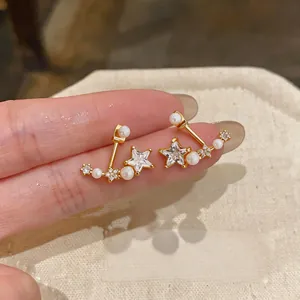 Dettaglio degli orecchini a stella con zirconi e perle bianche su finitura oro