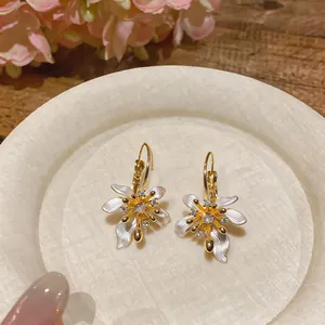 Detailed close-up of French retro flower earrings with white enamel and zircons.