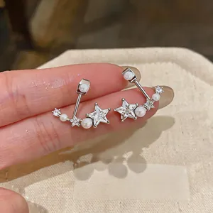 Dettaglio di orecchini a stella in argento con zirconi e delicate perle bianche