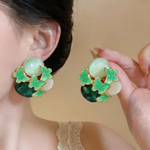 Close-up of green enamel butterfly earrings with cat's eye stones and faceted gems