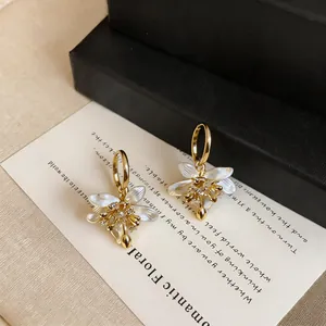 Detail of vintage zircon oil-drop flower earrings featuring white petals and gold hoops
