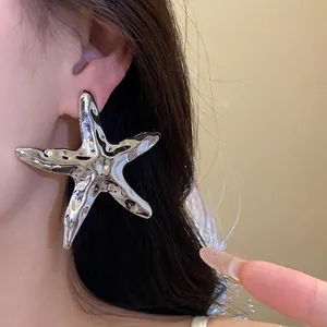 Große silberne Seestern-Ohrringe mit einem zerknitterten Metallic-Finish am Ohr